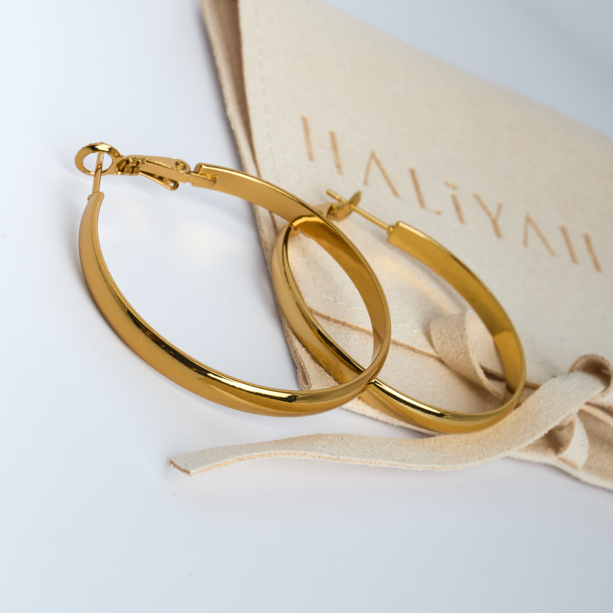 Gold hoop earrings on a Haliyali branded box with ribbon