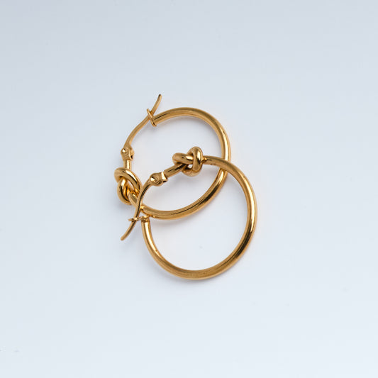 Gold hoop earring on a light gray background