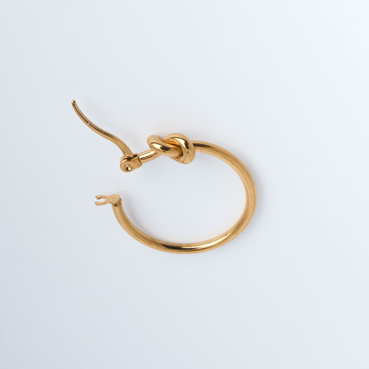 Gold hoop earring on a light gray background