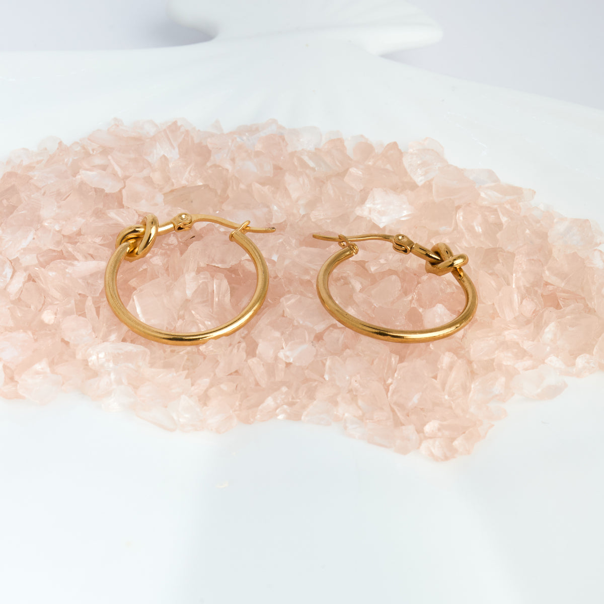 Gold hoop earrings on a pink crystal background