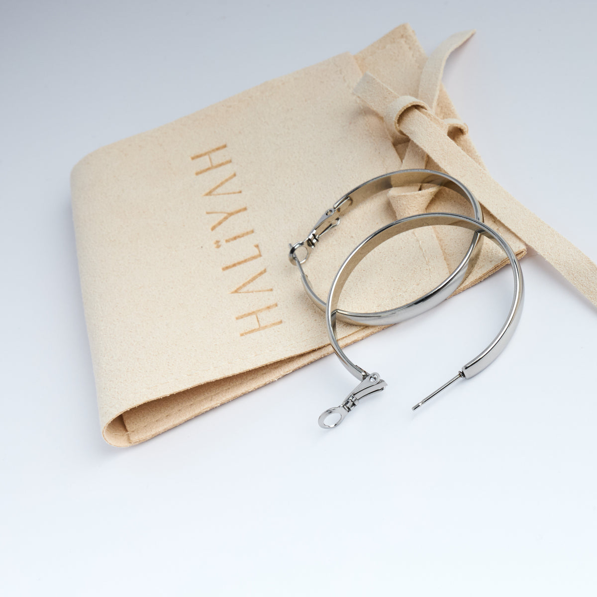 Silver hoops on a HAYLIYAH-branded jewellery pouch with a white background